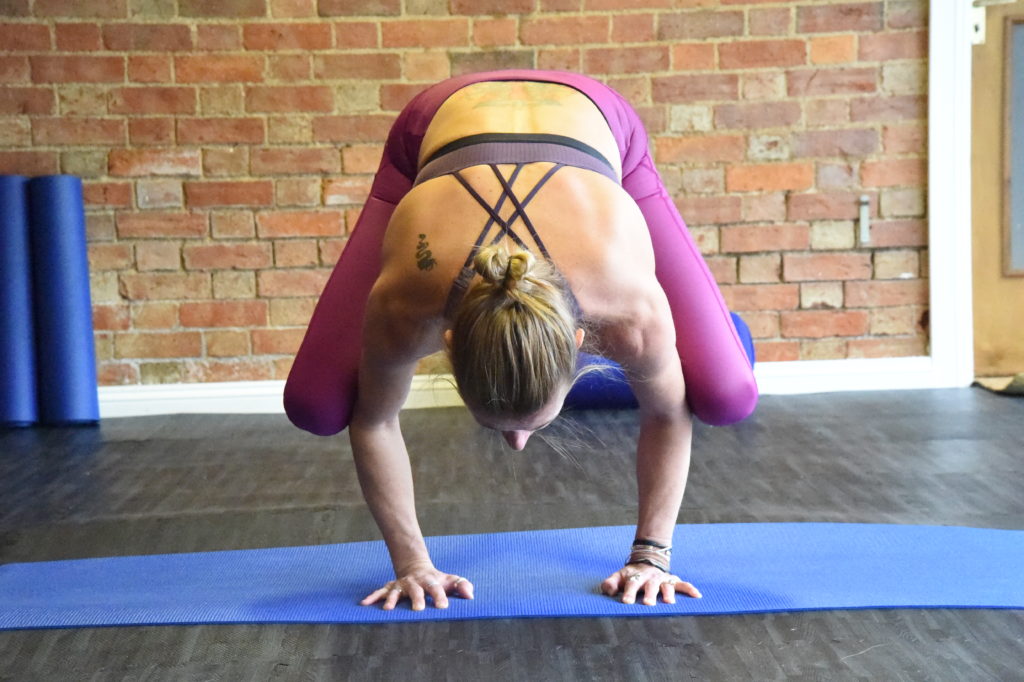 Lady doing a yoga pose balancing on both hands